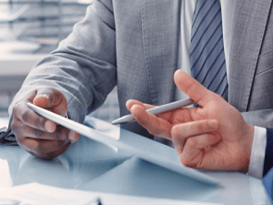 whychooseusnew A man in a suit and tie holding two pens